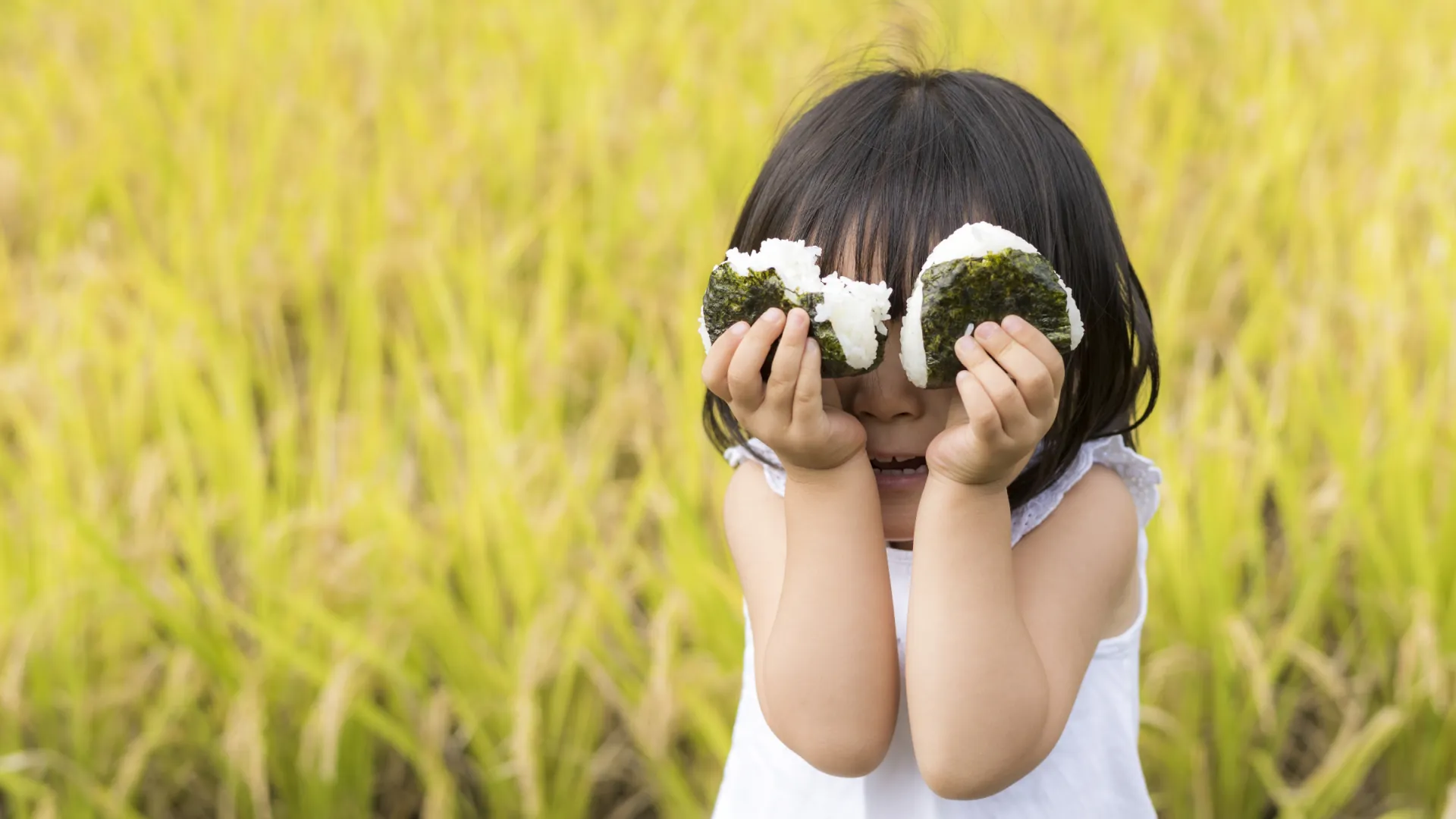 ⑤田んぼでおにぎりを食べる子供